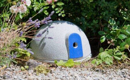 Runde Hummelburg aus einem granitähnlichen Material und einem blauen Einflugbereich in einem Garten